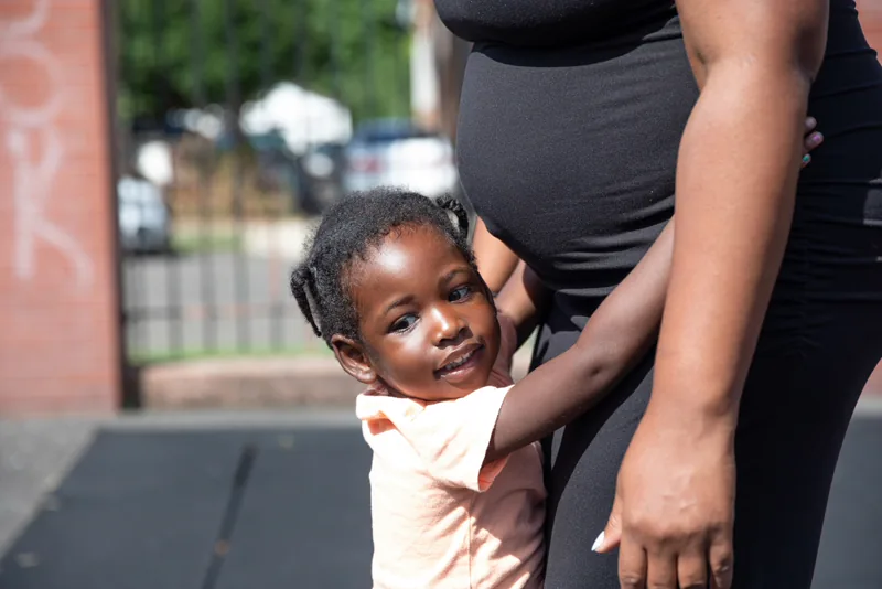 A toddler beside their expecting mother.