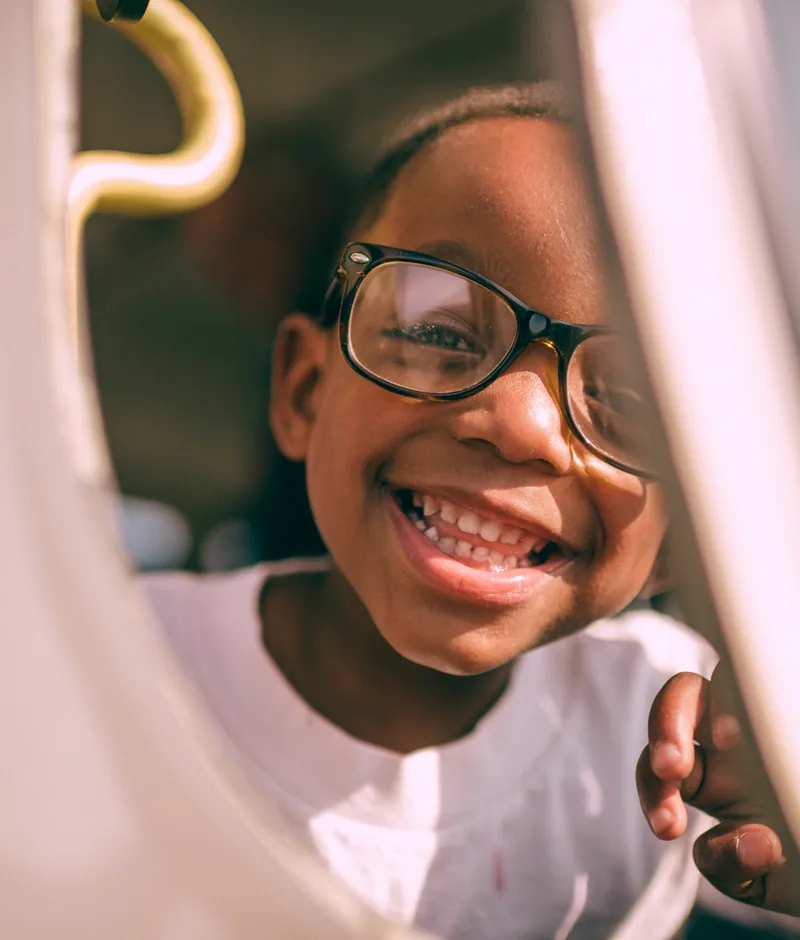 A girl in glasses smiling warmly.