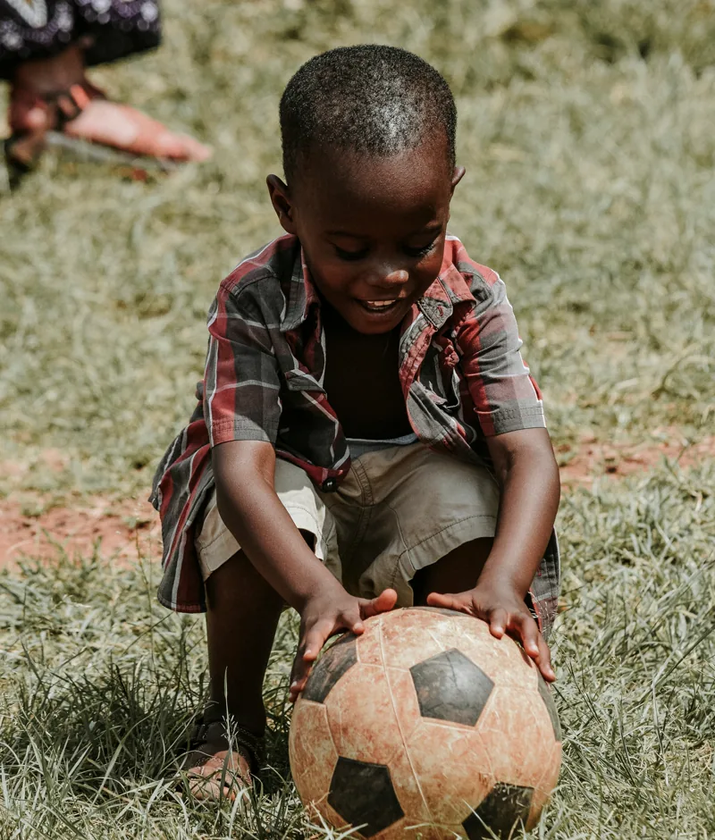 A boy playing with a football outdoors.